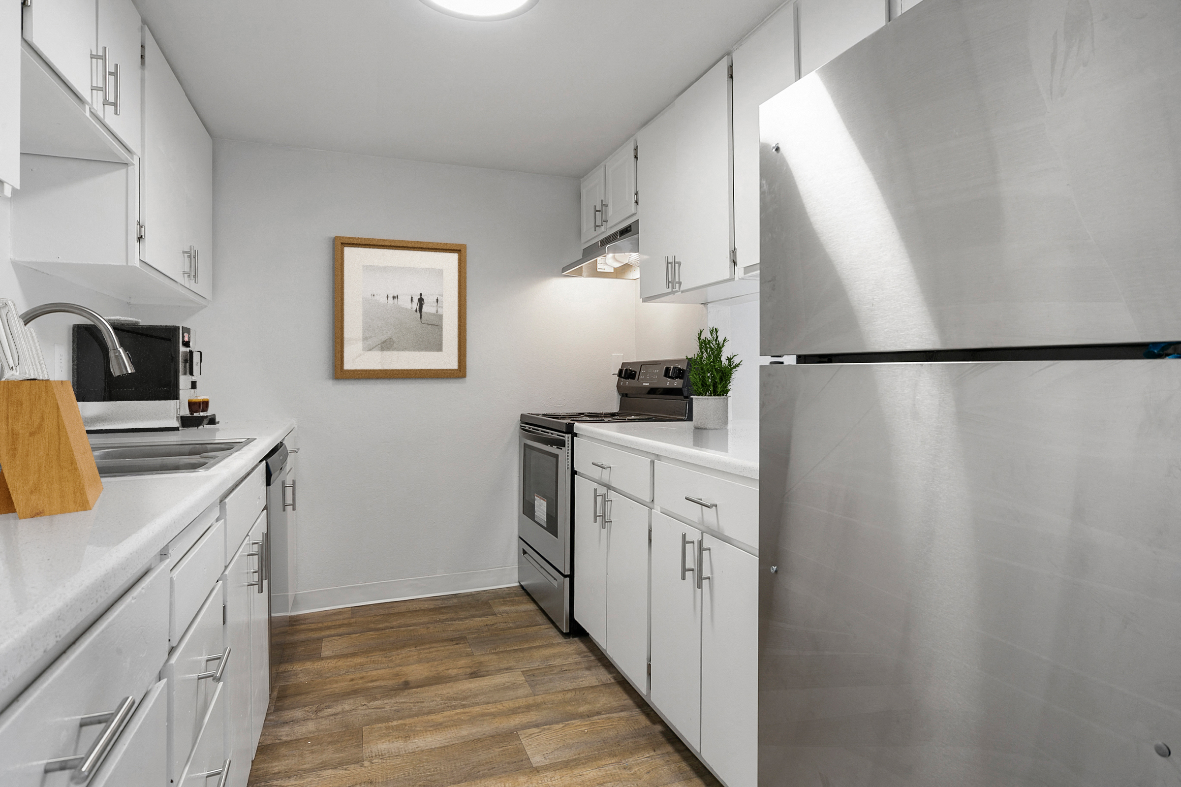 A modern kitchen with stainless steel appliances and wooden floors.